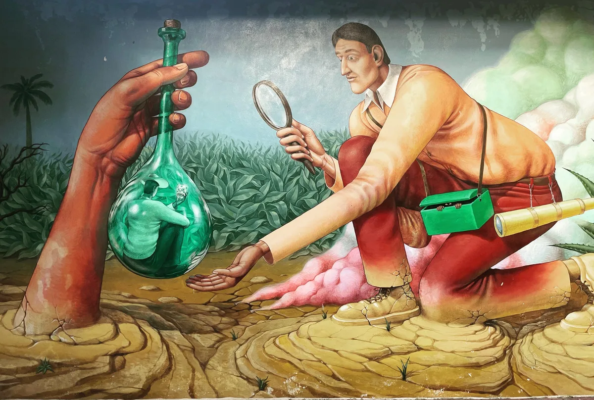 A wide mural of a kneeling figure and a large hand holding a green glass bottle, painted in bright colours
