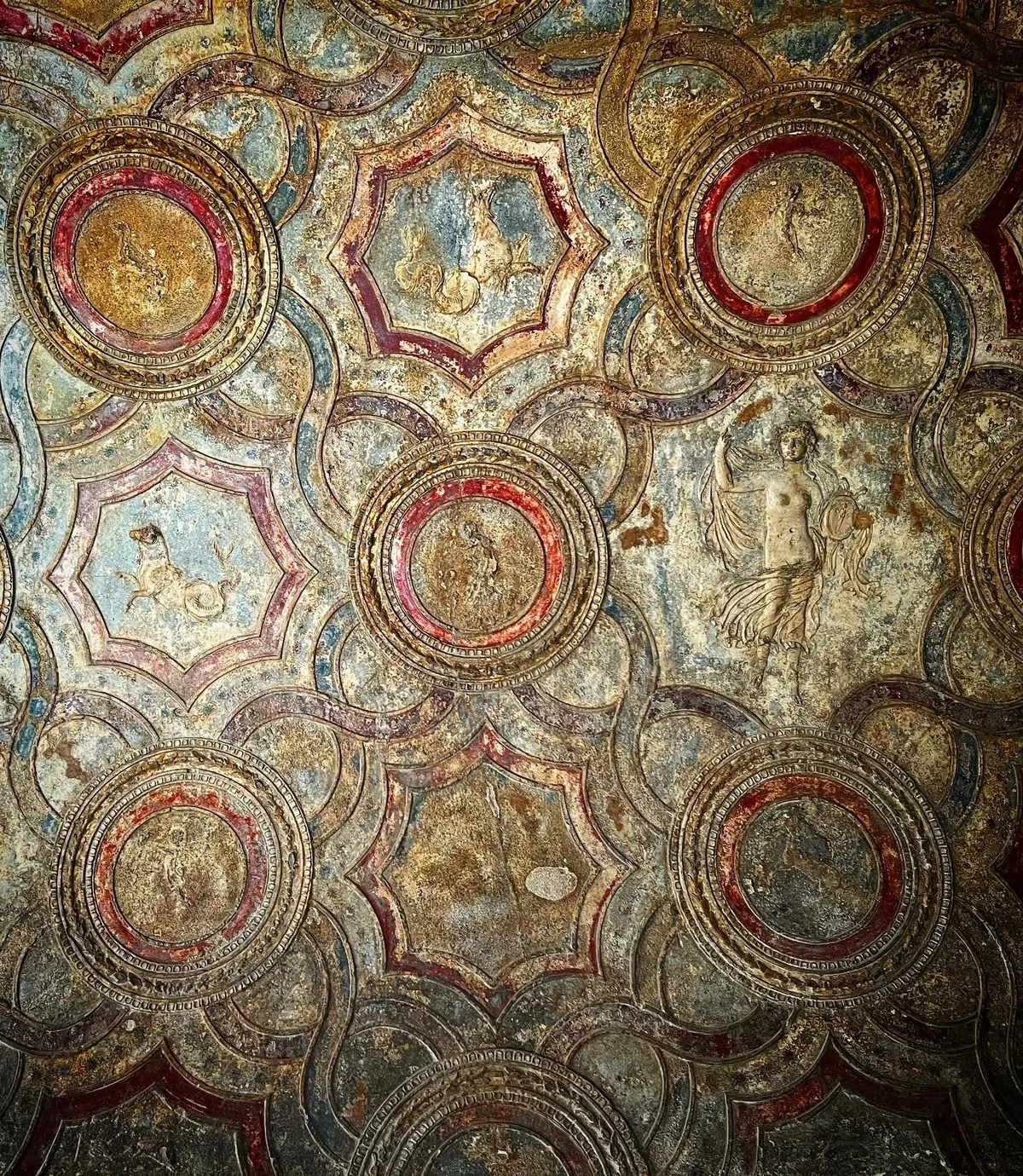 A Pompeii ceiling painted with repeating circular medallions in red, blue, and ochre