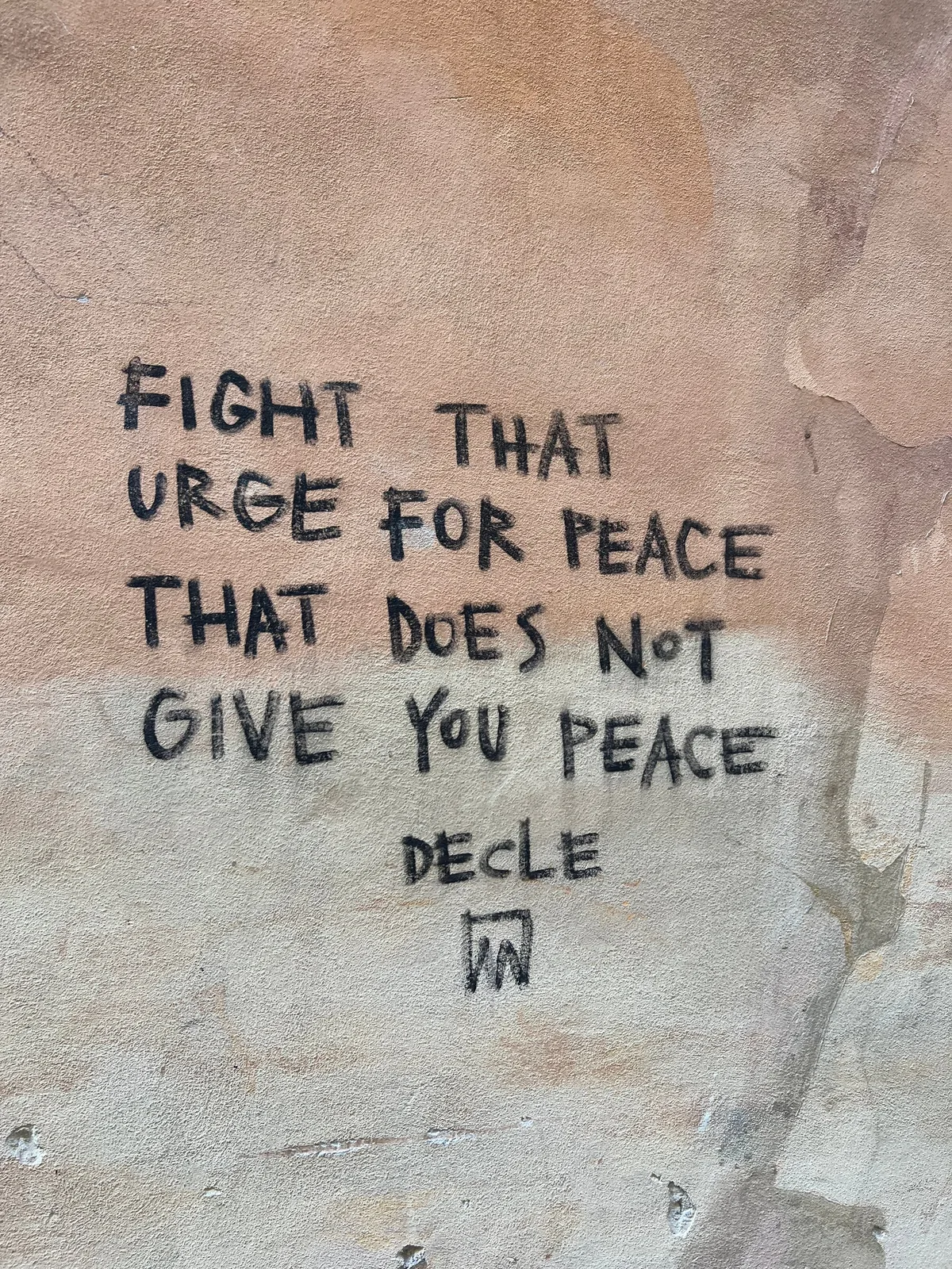 Handwritten words on a pale wall in Rome: fight that urge for peace that does not give you peace