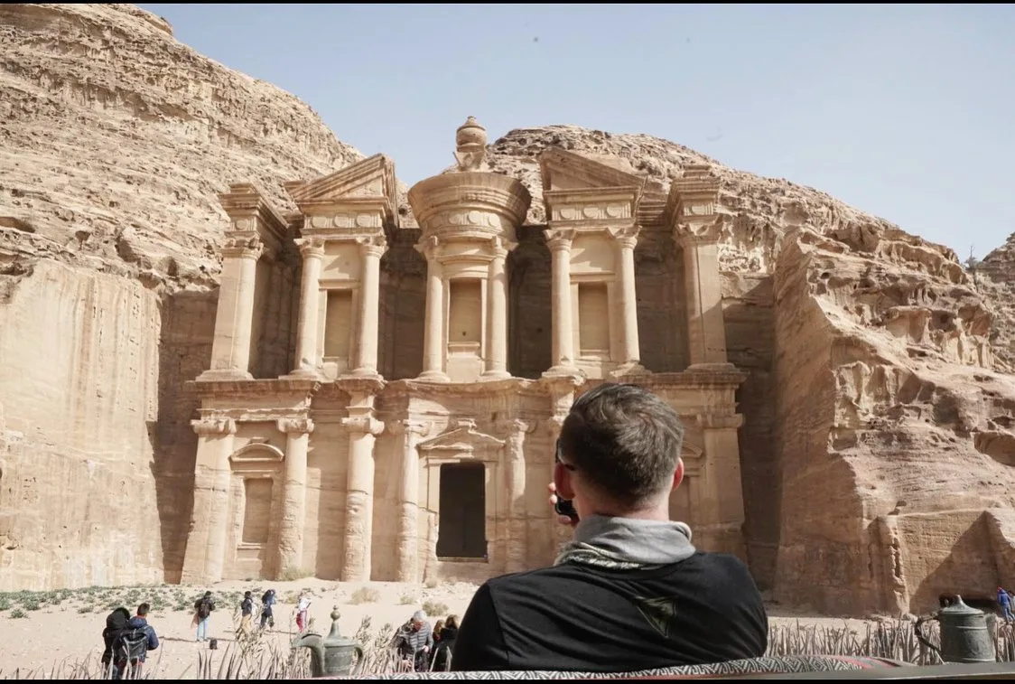 The Monastery at Petra, a broad carved facade in pale rock, with a person in the foreground looking up at it